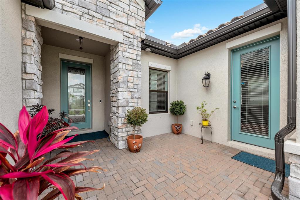 A covered outdoor patio features a blue kitchen cabinet unit, a grill, and a dining set — 2028 WOODLEAF HAMMOCK COURT, BRADENTON, FL