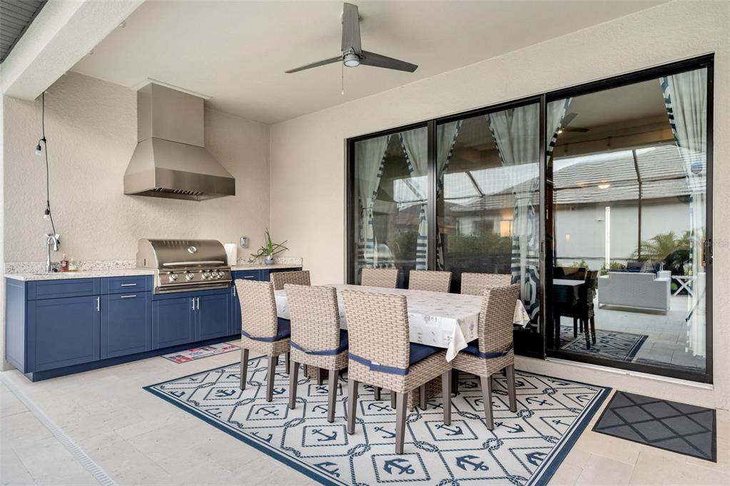 An outdoor kitchen features blue cabinets, a stainless steel grill, and a granite countertop — 2028 WOODLEAF HAMMOCK COURT, BRADENTON, FL