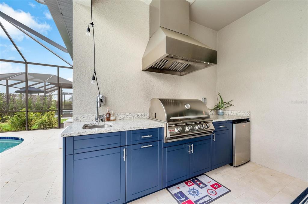A screened-in patio features a swimming pool, outdoor kitchen, and dining area — 2028 WOODLEAF HAMMOCK COURT, BRADENTON, FL