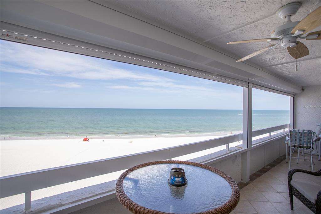A balcony with a glass-topped table and ceiling fan overlooks a sandy beach and ocean — 17940 GULF BOULEVARD UNIT 6E, REDINGTON SHORES, FL