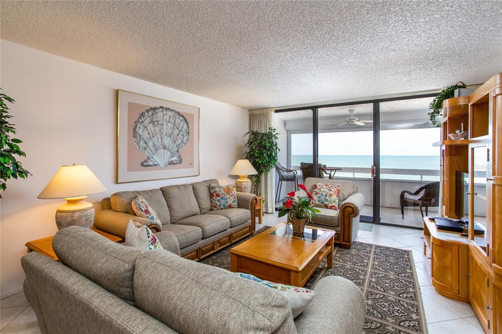 A living room with a sofa, armchair, coffee table, and a balcony overlooking the ocean — 17940 GULF BOULEVARD UNIT 6E, REDINGTON SHORES, FL