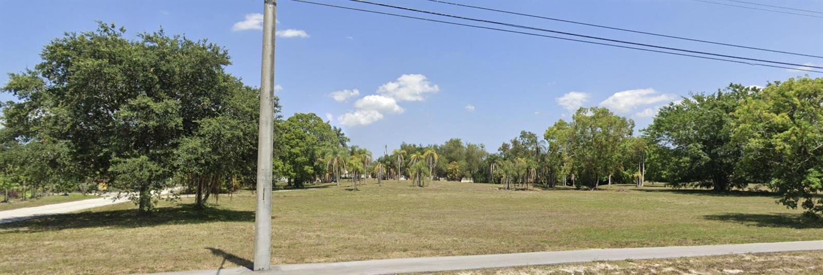 A wide, grassy vacant lot features scattered trees and palm trees under a blue sky — 16650 Velazquez Boulevard, Loxahatchee FL 33470, LOXAHATCHEE, FL