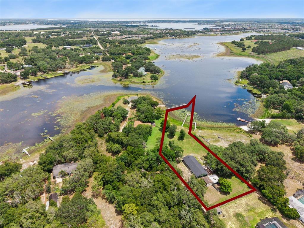 An aerial view shows a house on a large, tree-filled lot bordering a lake — 3421 REX DRIVE, WINTER GARDEN, FL