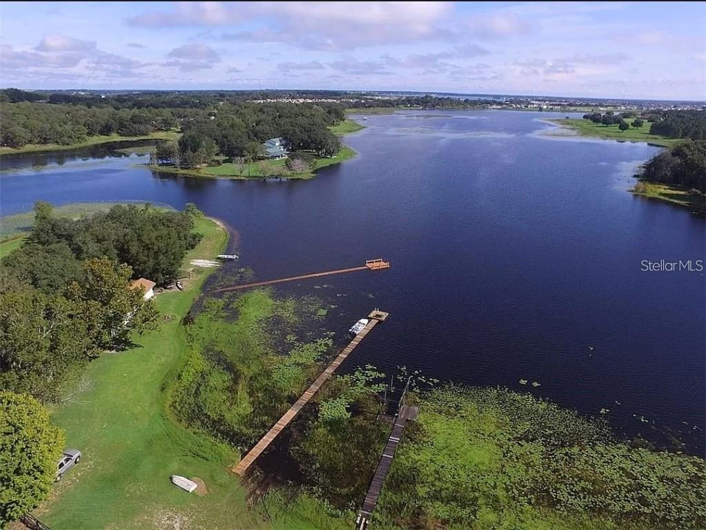 An aerial view shows a house on a large, grassy lot bordering a lake — 3421 REX DRIVE, WINTER GARDEN, FL