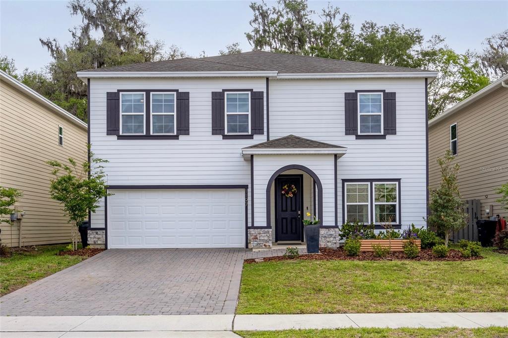 A two-story white house with a two-car garage, dark shutters, and an arched entryway — 1197 NW 133RD WAY, NEWBERRY, FL