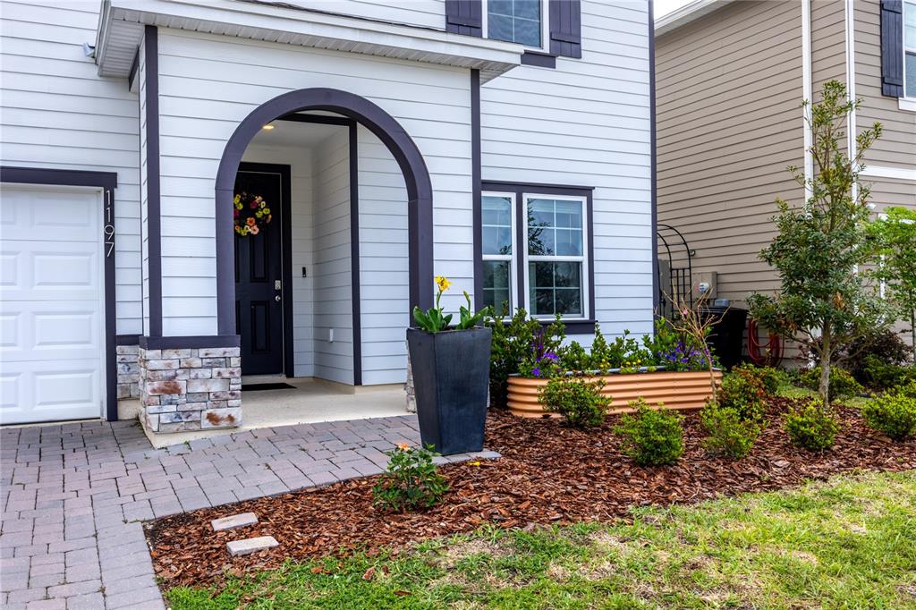 The exterior of a white house features a dark arched entryway and a stone base — 1197 NW 133RD WAY, NEWBERRY, FL