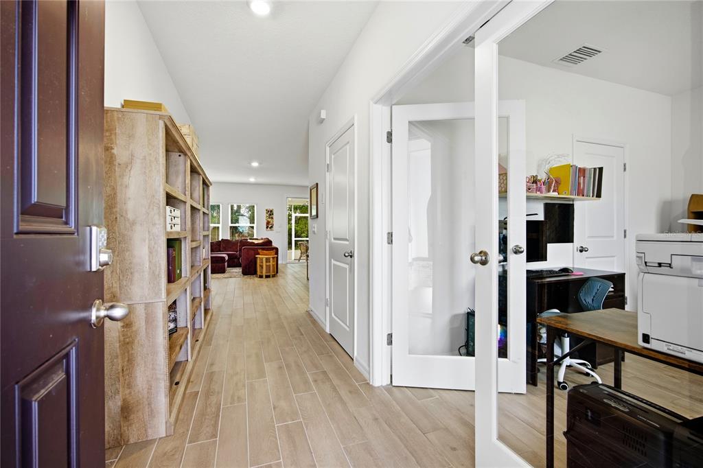 An entryway leads to a hallway with a bookshelf, a home office, and a living area — 1197 NW 133RD WAY, NEWBERRY, FL