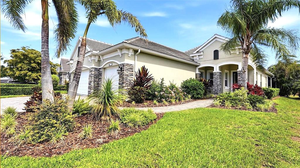 A single-story house with a stone facade, palm trees, and a landscaped front yard — 519 WILDLIFE GLEN, BRADENTON, FL