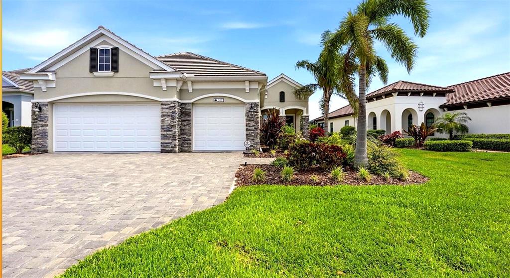 A suburban house with a stone-accented facade, two garage doors, and a landscaped front yard — 519 WILDLIFE GLEN, BRADENTON, FL