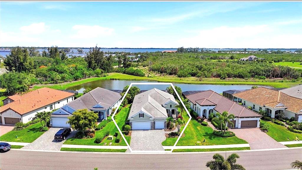 An aerial view shows a suburban house with a white garage facing a small pond — 519 WILDLIFE GLEN, BRADENTON, FL