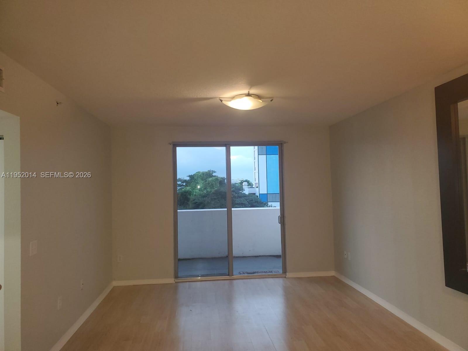An empty room features light wood flooring, neutral walls, and a sliding glass door to a balcony — 36 NW 6th Ave # 603, Miami FL 33128, MIAMI, FL
