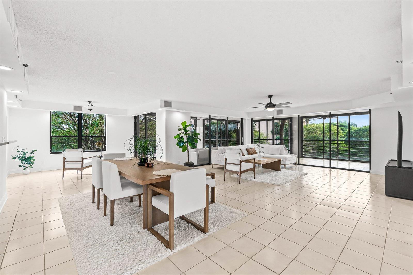 A bright, open-concept living and dining area features white tile floors and large sliding glass doors — 7201 Promenade Drive E # 302, Boca Raton FL 33433, BOCA RATON, FL