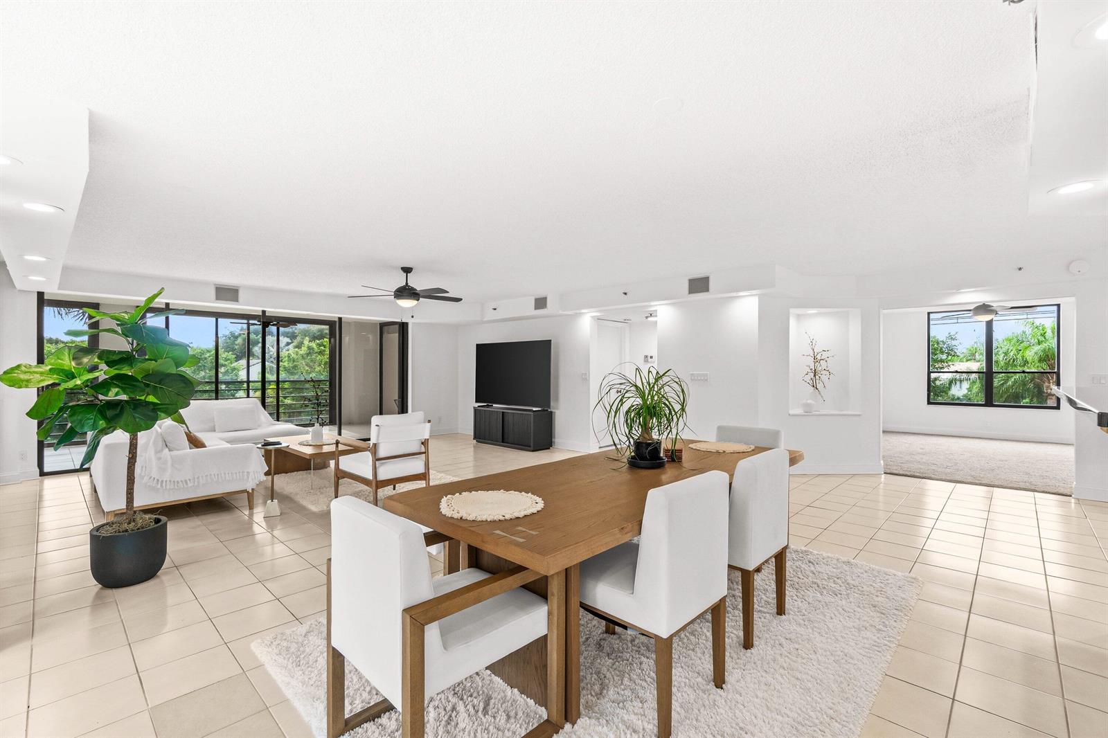 A bright, open-concept living and dining area features tile flooring, white furniture, and large windows — 7201 Promenade Drive E # 302, Boca Raton FL 33433, BOCA RATON, FL