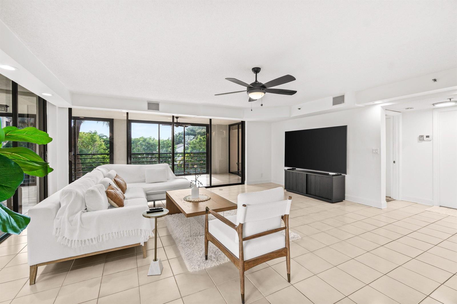 A bright living room features white tile floors, a white sectional sofa, and floor-to-ceiling windows — 7201 Promenade Drive E # 302, Boca Raton FL 33433, BOCA RATON, FL