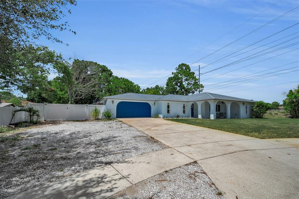 A single-story house with a blue garage door, white exterior, and a concrete driveway — 505 WHISPERING OAK DRIVE, TARPON SPRINGS, FL