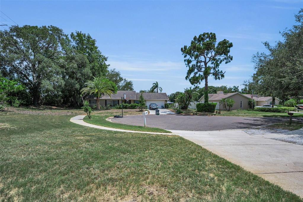 A single-story house sits at the end of a cul-de-sac with a large front lawn — 505 WHISPERING OAK DRIVE, TARPON SPRINGS, FL