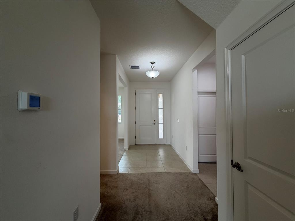 A foyer features a front door with a sidelight, tiled flooring, and a carpeted hallway — 416 SAPPHIRE DR, DAVENPORT, FL