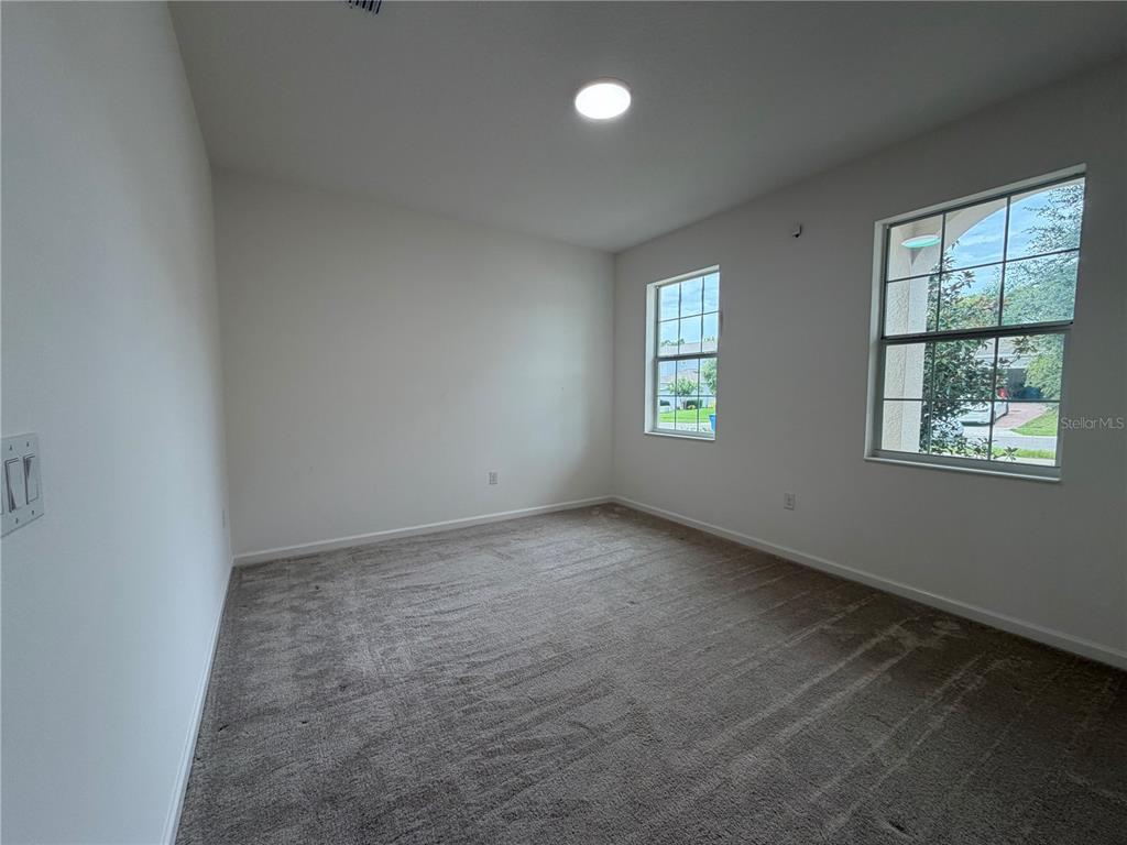 An empty bedroom features white walls, gray carpeting, two windows, and a ceiling light — 416 SAPPHIRE DR, DAVENPORT, FL