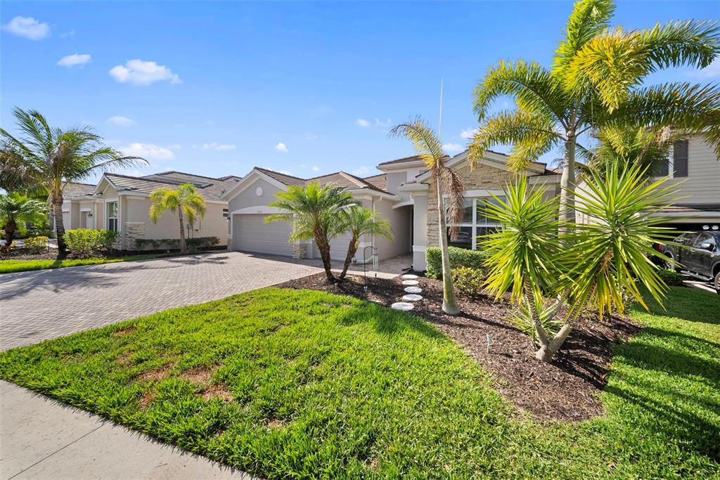 A single-story house with a paved driveway, palm trees, and a landscaped front yard — 16378 BONITA LANDING CIRCLE, BONITA SPRINGS, FL