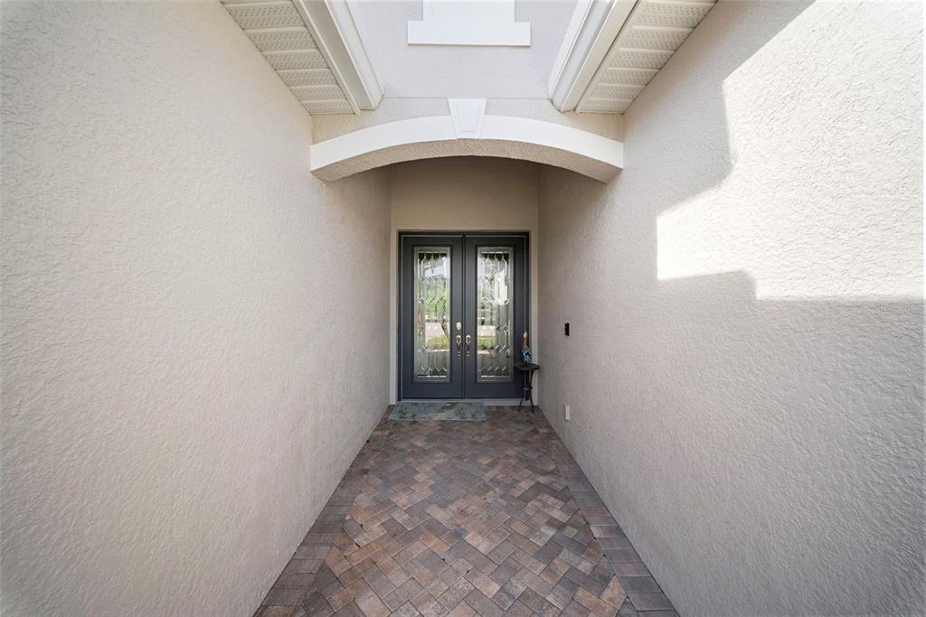 A covered entryway features a brick paver floor and a dark double door with glass — 16378 BONITA LANDING CIRCLE, BONITA SPRINGS, FL