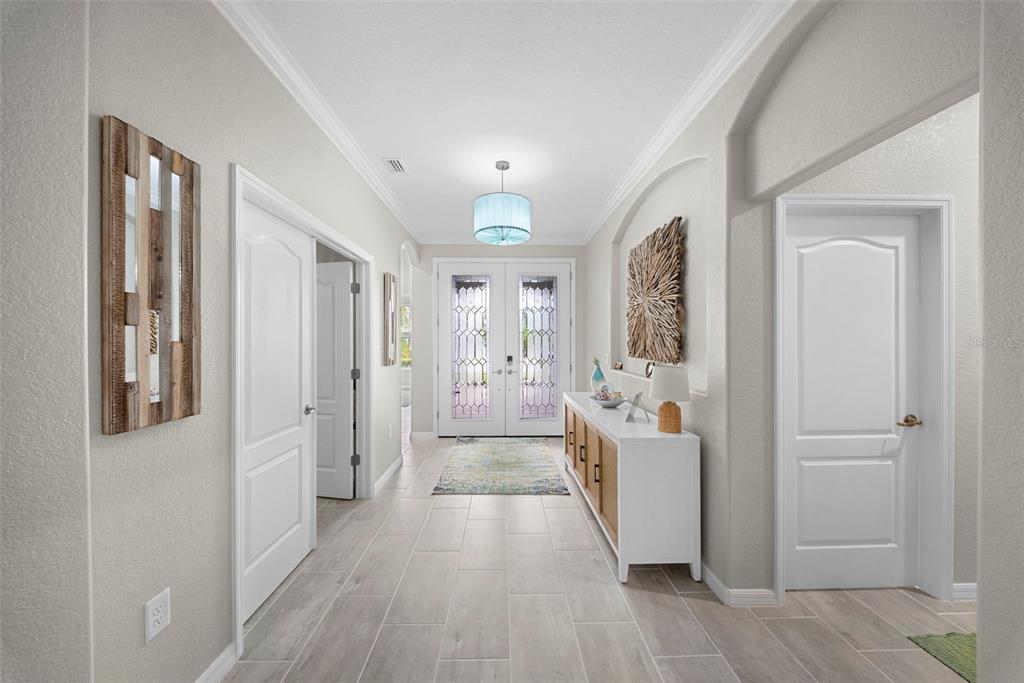 A bright foyer features light tile flooring, a white console table, and double glass doors — 16378 BONITA LANDING CIRCLE, BONITA SPRINGS, FL
