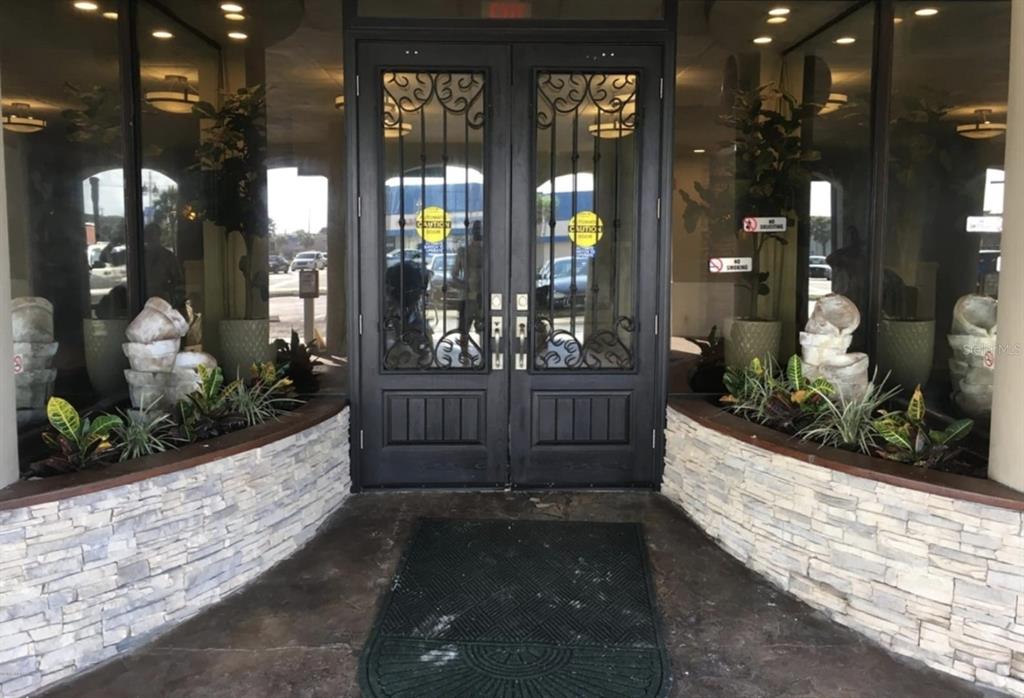 The exterior entrance features double glass doors with iron grilles flanked by stone planters — 3501 S ATLANTIC AVENUE UNIT 5030, DAYTONA BEACH, FL