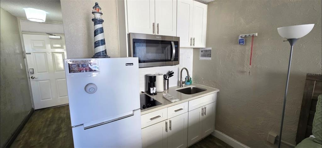 A small kitchenette features white cabinets, a stainless steel microwave, and a white refrigerator — 3501 S ATLANTIC AVENUE UNIT 5030, DAYTONA BEACH, FL