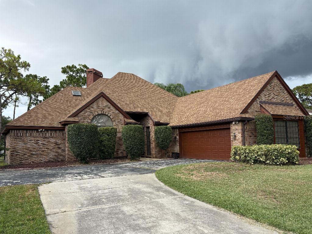 A single-story brick house with a brown shingled roof and an attached two-car garage — 10484 LONGWOOD DRIVE, SEMINOLE, FL
