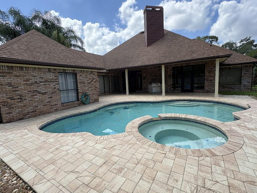 A brick house with a brown roof, a swimming pool, and a spa on a patio — 10484 LONGWOOD DRIVE, SEMINOLE, FL