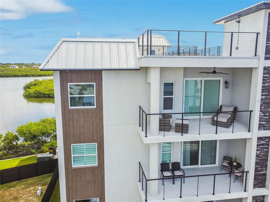 An exterior view of a multi-story building with balconies overlooking a body of water — 19505 GULF BOULEVARD UNIT 404, INDIAN SHORES, FL