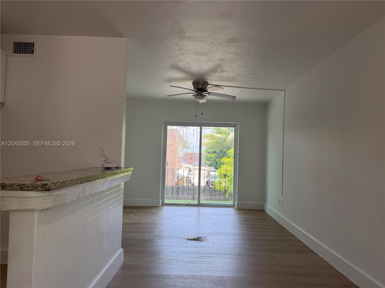 An empty room features light wood-look flooring, a ceiling fan, and a sliding glass door — 1021 NW 5th St # 6, Miami FL 33128, MIAMI, FL