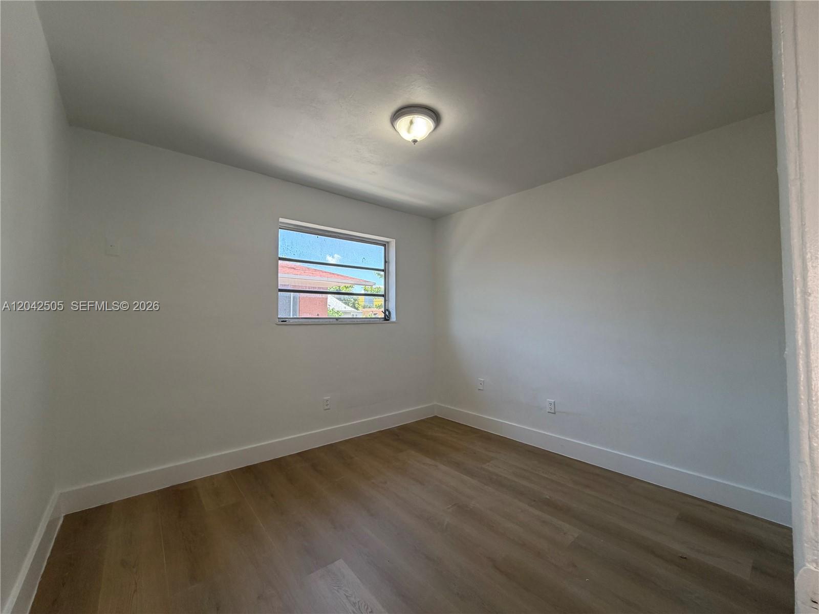 An empty room features white walls, light wood-look flooring, and a single window — 1021 NW 5th St # 6, Miami FL 33128, MIAMI, FL