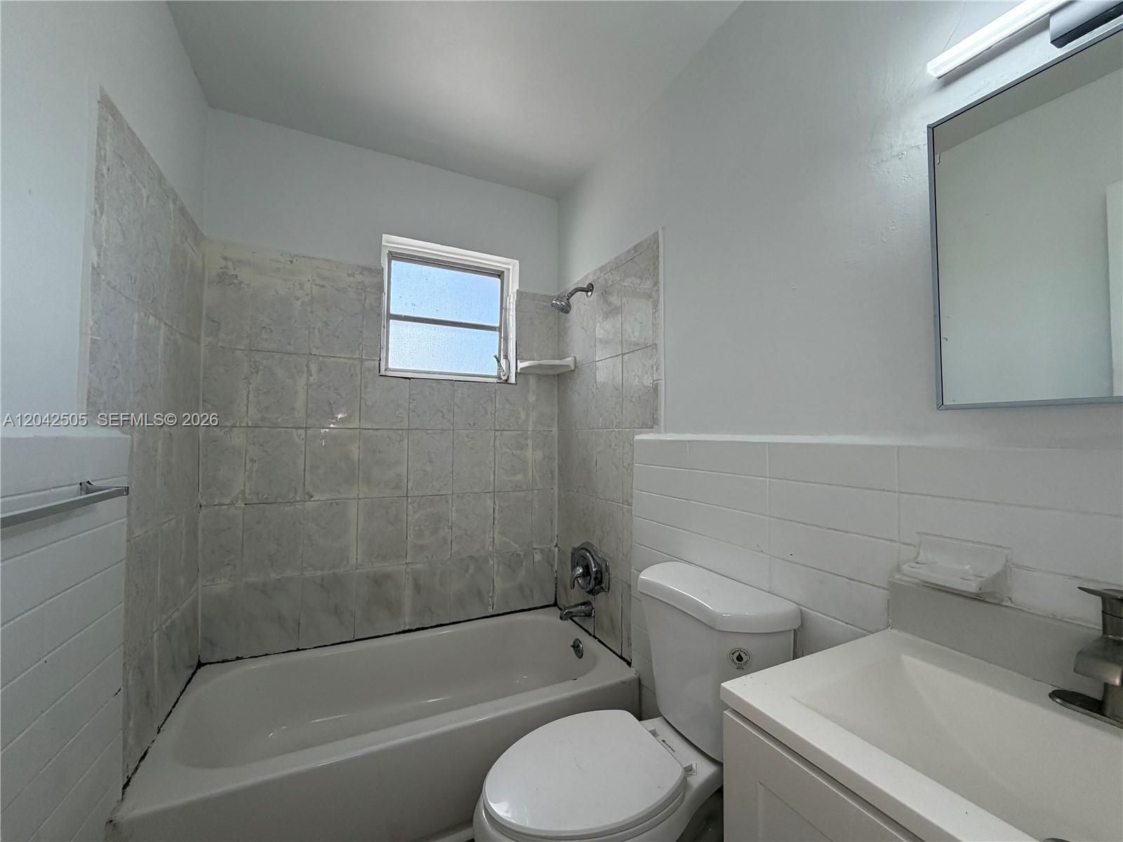 A small bathroom features a white bathtub, a toilet, and a vanity with a mirror — 1021 NW 5th St # 6, Miami FL 33128, MIAMI, FL