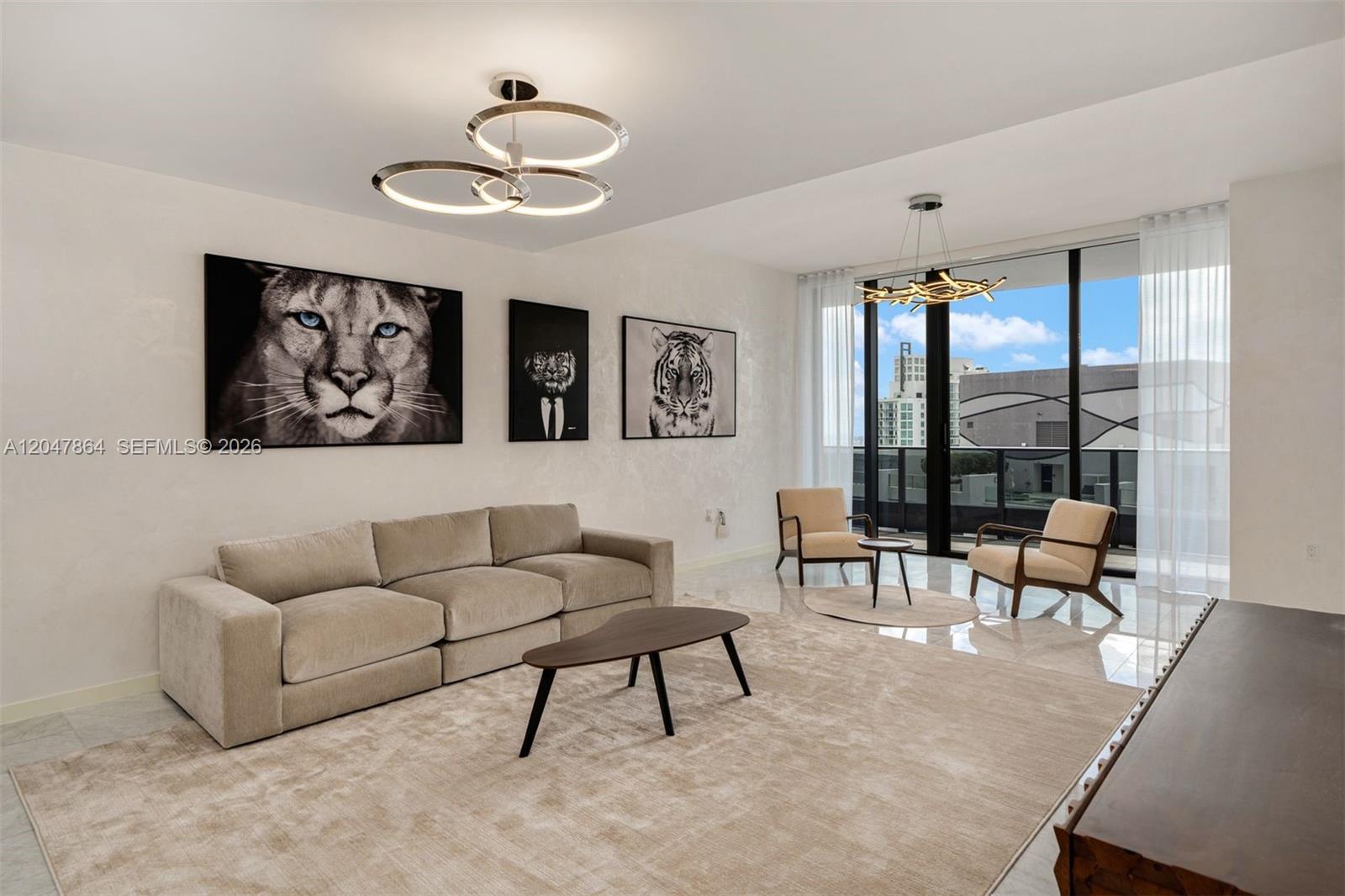 A modern living room features a beige sofa, three animal portraits, and floor-to-ceiling windows — 1000 Brickell Plz, Miami FL 33131, MIAMI, FL