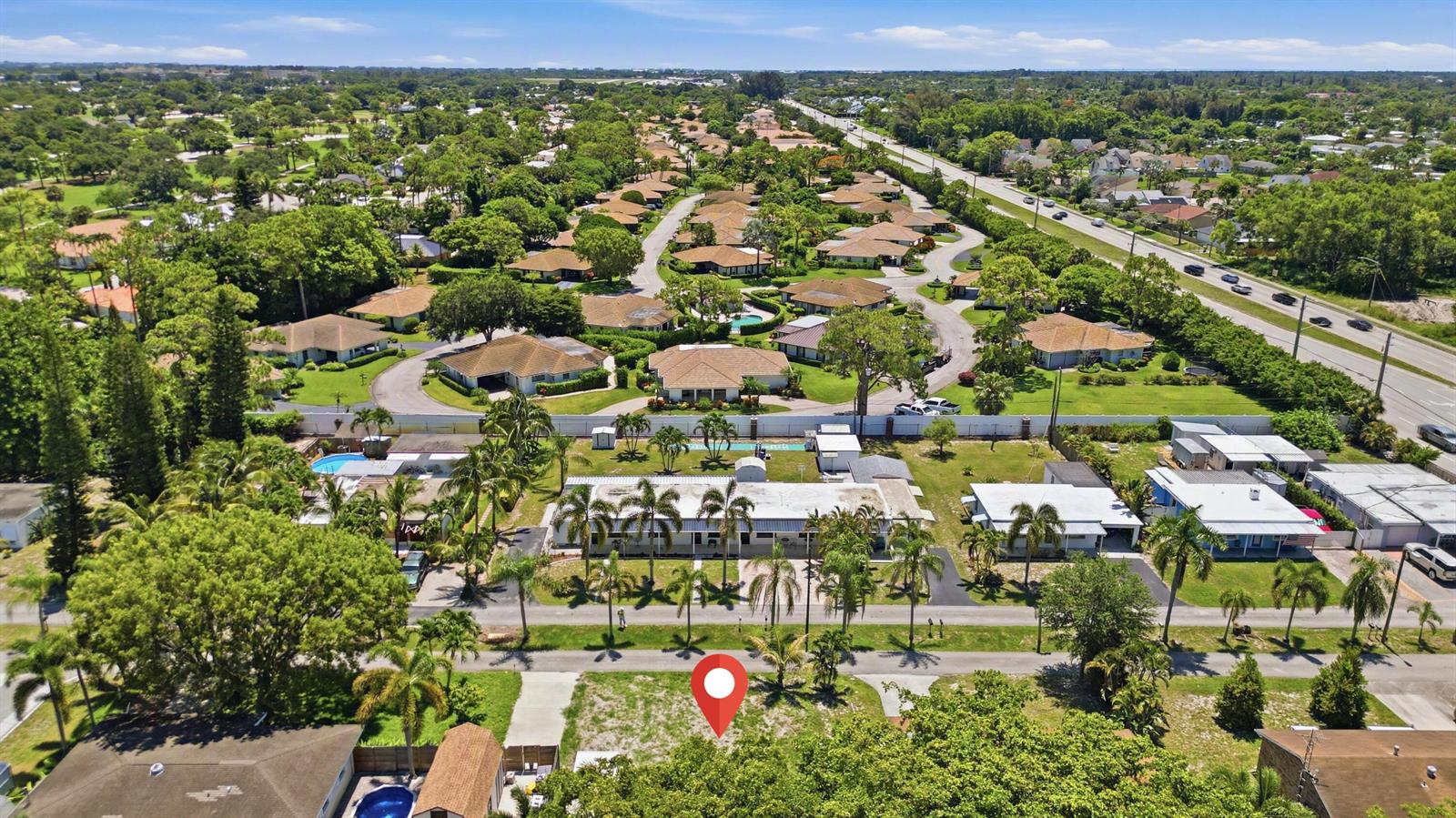 An aerial view shows a vacant residential lot marked with a red pin near houses — 000 Morrison Avenue, FL 33463, FL