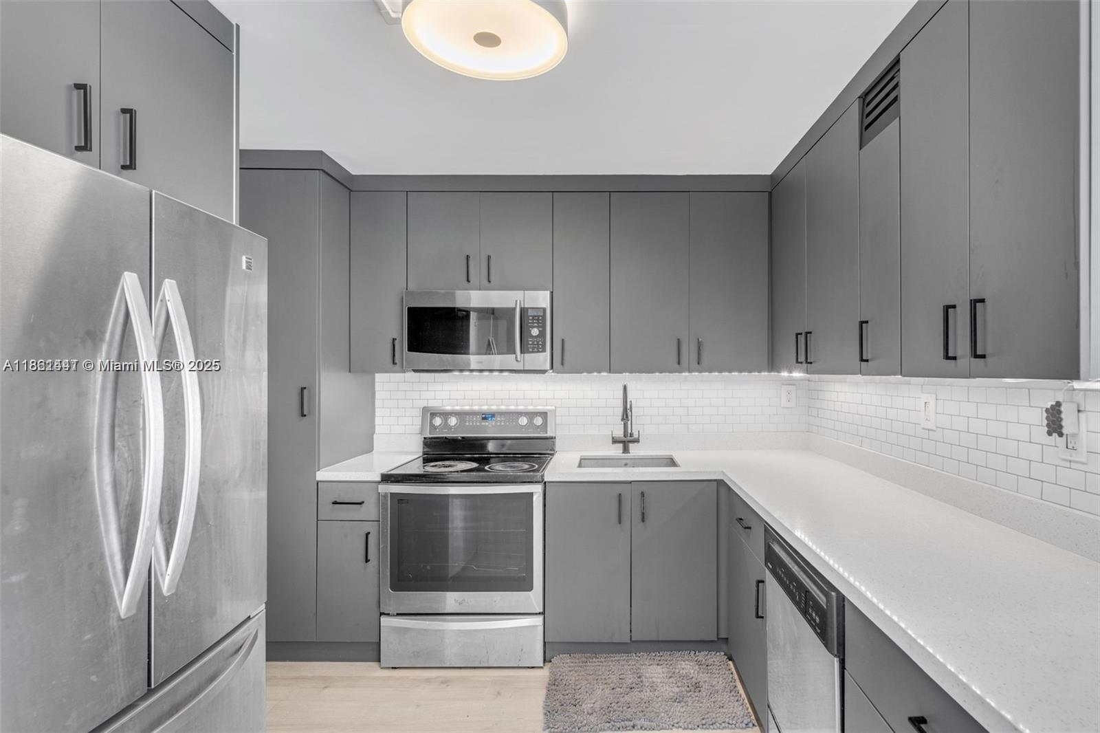 A modern kitchen features gray cabinetry, stainless steel appliances, and white subway tile backsplashes — 6900 Bay Dr # 11F, Miami Beach FL 33141, MIAMI BEACH, FL