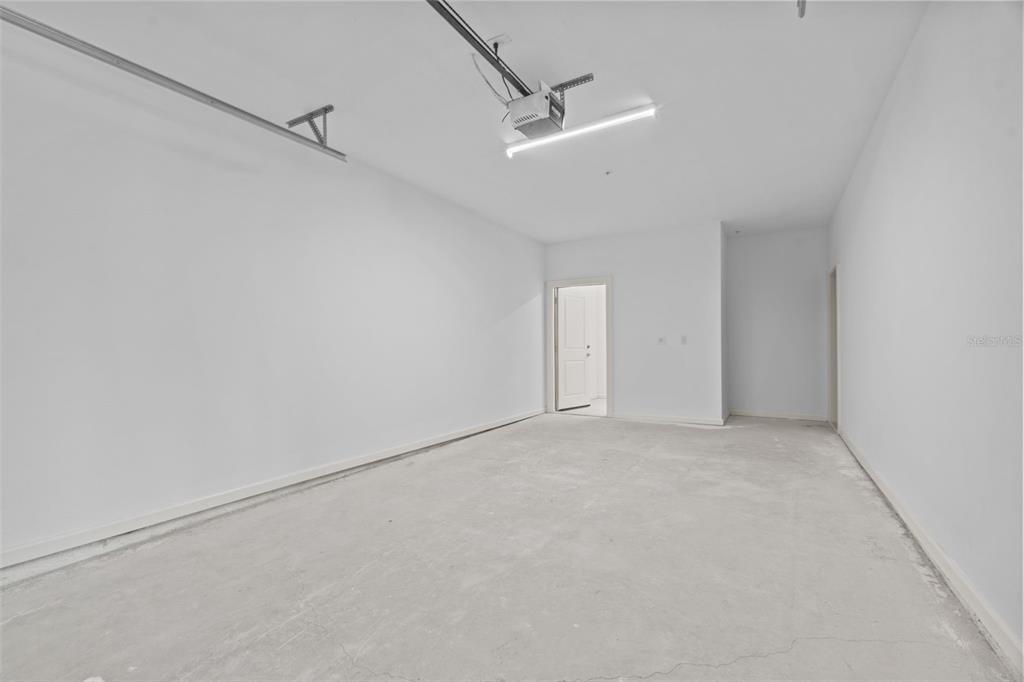 An empty, unfinished garage with white walls, concrete flooring, and a ceiling-mounted light fixture — 1700 RANCH ROAD UNIT B4-8202, NOKOMIS, FL