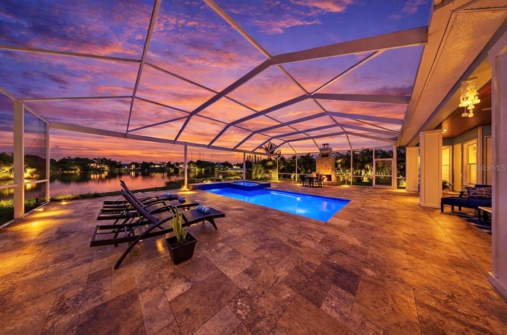 A blue house with a metal roof and front porch at sunset by a lake — 8013 KEY WEST CONCH DRIVE, RIVERVIEW, FL