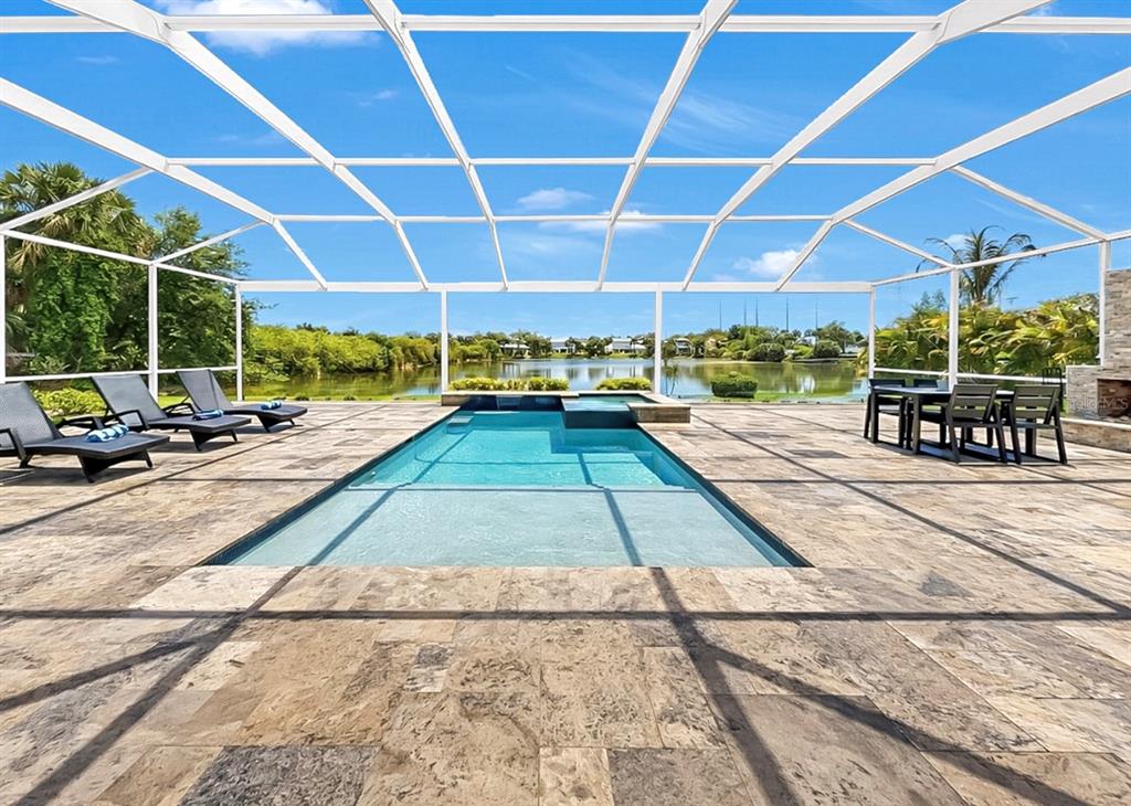 A covered patio features a swimming pool, stone pavers, and a view of a lake — 8013 KEY WEST CONCH DRIVE, RIVERVIEW, FL