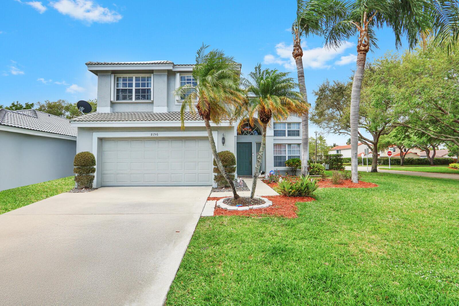 A two-story suburban house with a concrete driveway, palm trees, and a green front door — 8156 Mystic Harbor Circle, Boynton Beach FL 33436, BOYNTON BEACH, FL