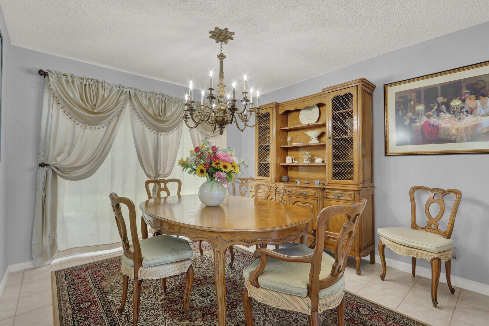 A dining room features a wooden table, chairs, a hutch, and a chandelier over a rug — 8156 Mystic Harbor Circle, Boynton Beach FL 33436, BOYNTON BEACH, FL