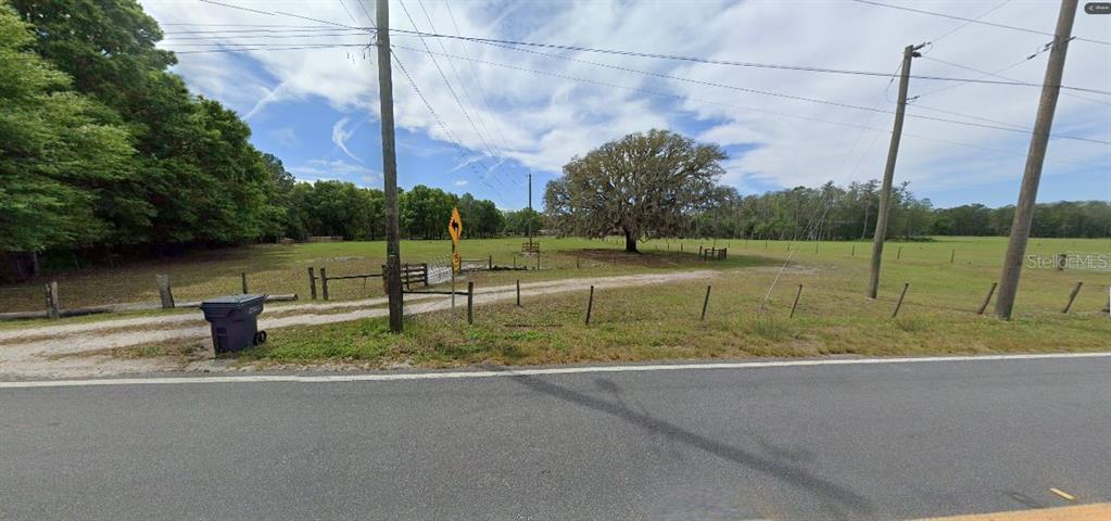 A gravel driveway leads through a gated fence into a large, grassy, tree-lined field — GREEN POND RD, POLK CITY, FL