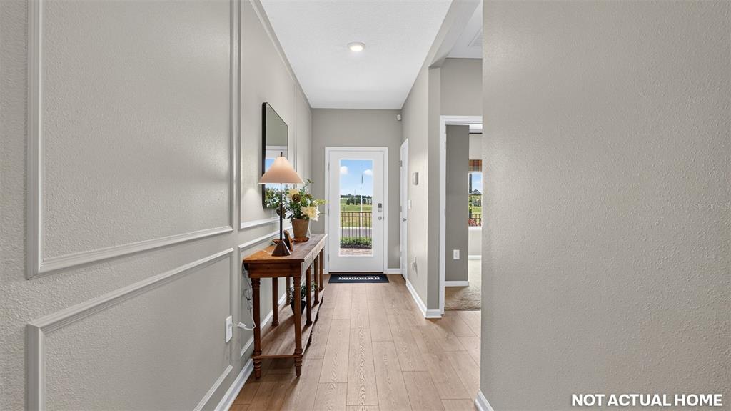 A hallway features wood-look flooring, wainscoting on the left wall, and a console table with decor — 238 HAWTHORN AVENUE, PALM COAST, FL