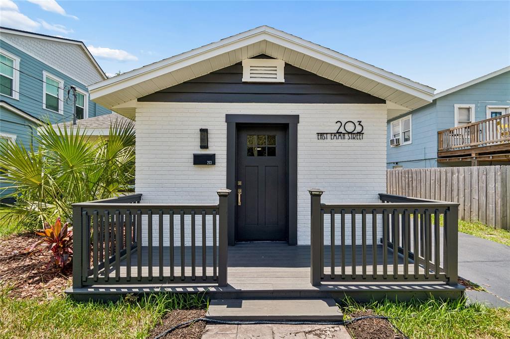 A small, white brick house features a dark gray front door and a wooden porch — 203 E EMMA STREET, TAMPA, FL