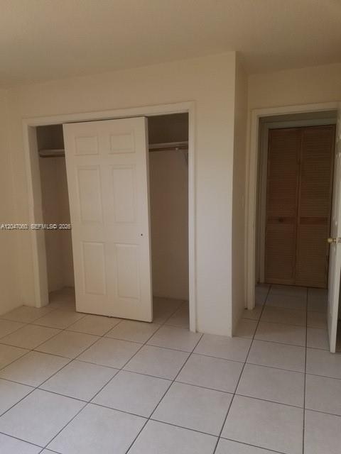 A room features white tiled floors, a white six-panel closet door, and a louvered door — 2230 Madison St # 14, Hollywood FL 33020, HOLLYWOOD, FL