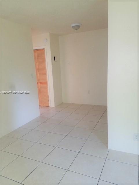 An empty room with light-colored tile flooring and a wooden louvered closet door — 2230 Madison St # 14, Hollywood FL 33020, HOLLYWOOD, FL