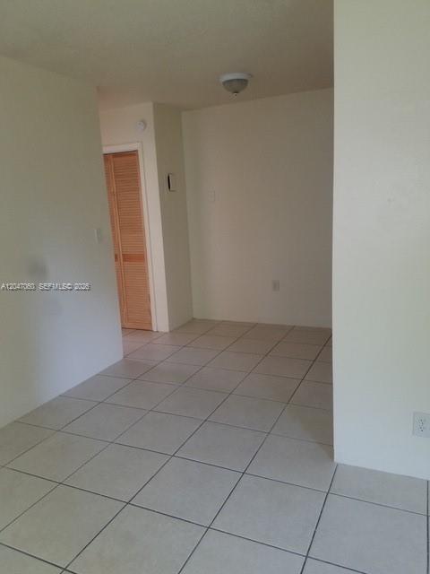 An empty room with light-colored floor tiles, white walls, and a wooden louvered closet door — 2230 Madison St # 14, Hollywood FL 33020, HOLLYWOOD, FL