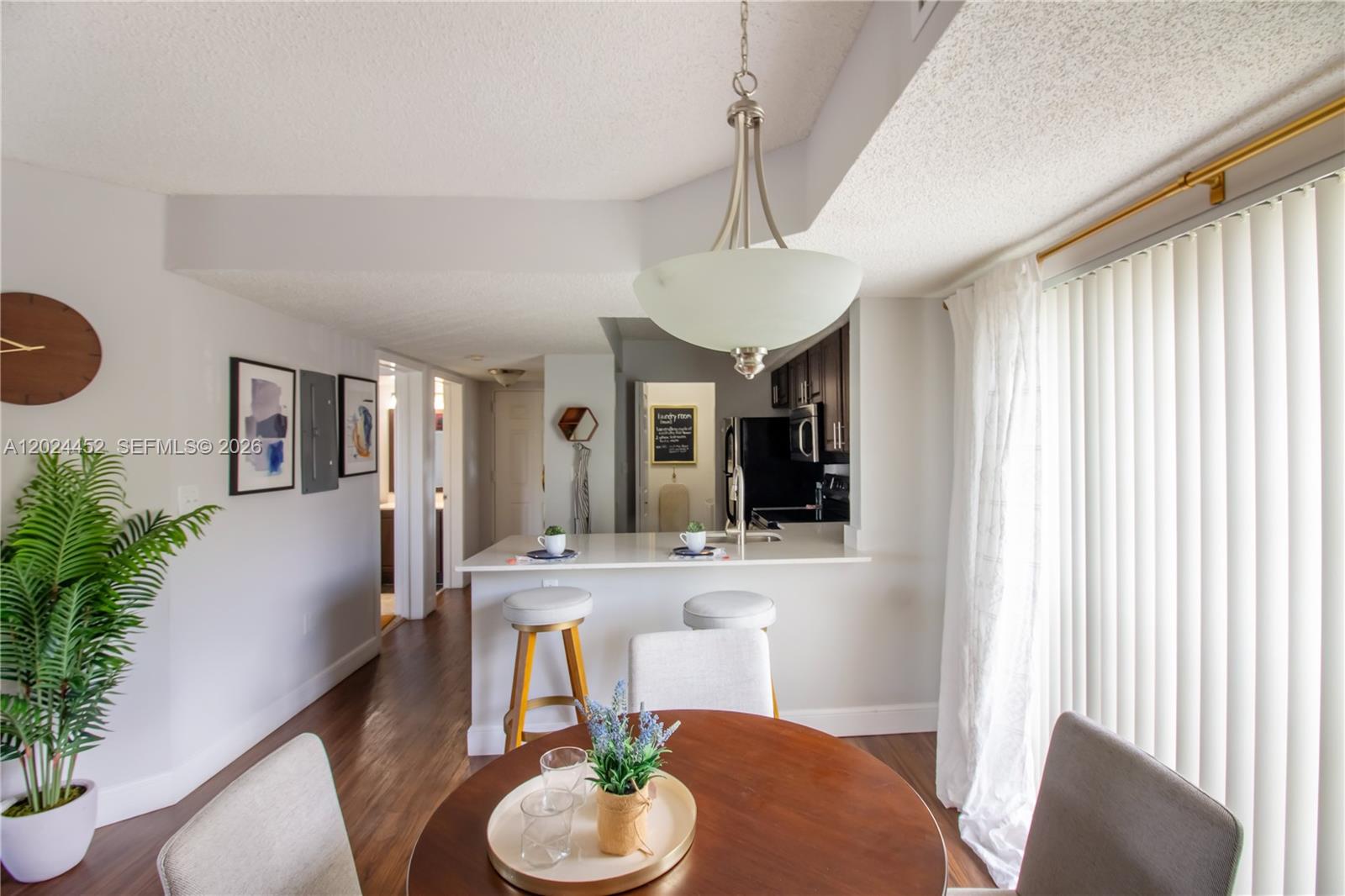 A dining area with a round table opens to a kitchen with a breakfast bar — 17230 NW 64th Ave, Miami Lakes FL 33015, MIAMI LAKES, FL