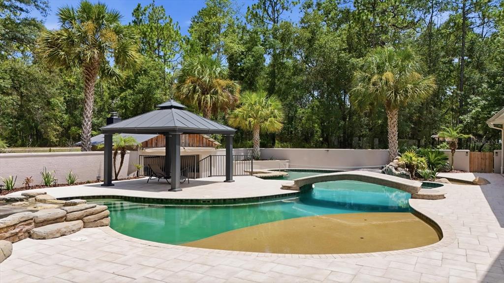 A backyard swimming pool features a gazebo, a stone bridge, and a tanning ledge — 91 S SCHOOL AVENUE, LECANTO, FL