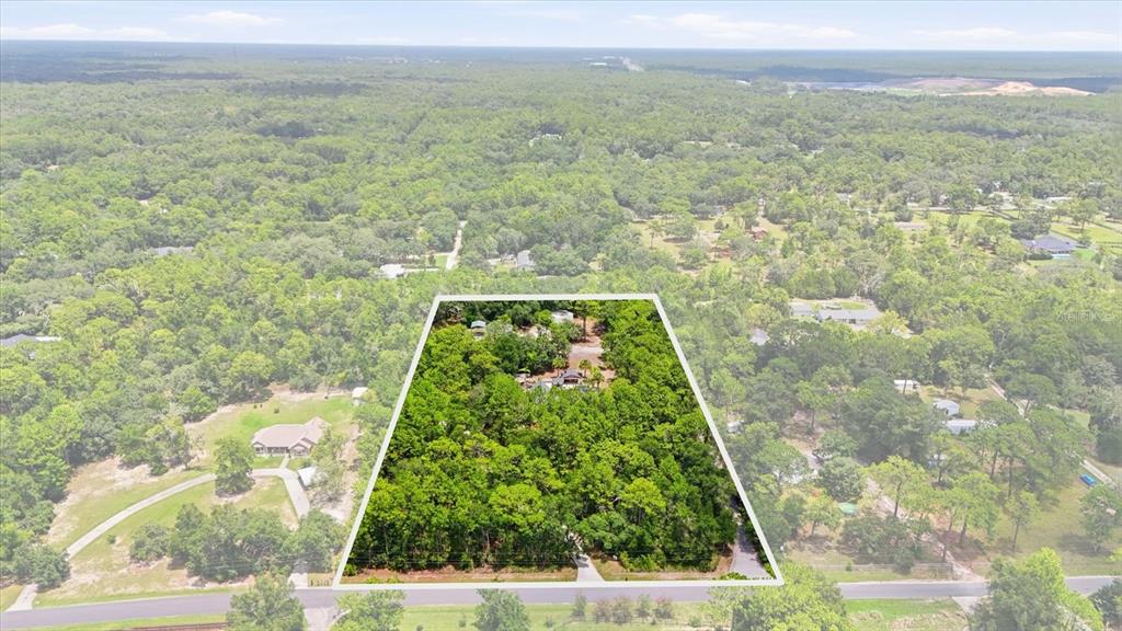 An aerial view shows a wooded residential lot outlined in white against a rural landscape — 91 S SCHOOL AVENUE, LECANTO, FL